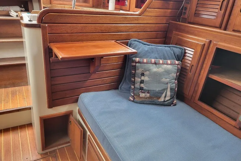 Slide: The Image of 1976 Down East Yachts Cutter interior with wooden paneling, blue cushion, and nautical-themed pillow. - 16