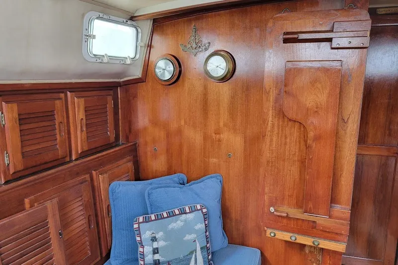 Slide: The Image of 1976 Down East Yachts Cutter interior with wooden paneling, blue cushions, and nautical decor. - 17