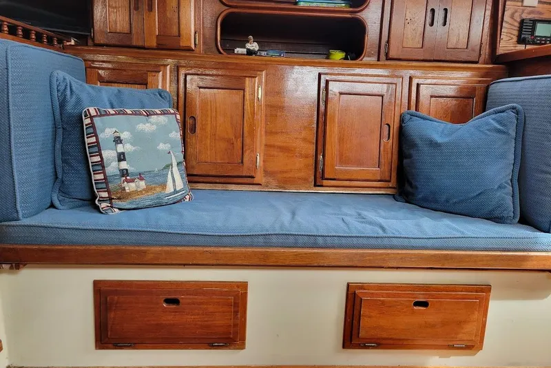 Slide: The Image of Cozy 1976 Down East Yachts Cutter interior with blue cushions and nautical-themed pillow. - 21