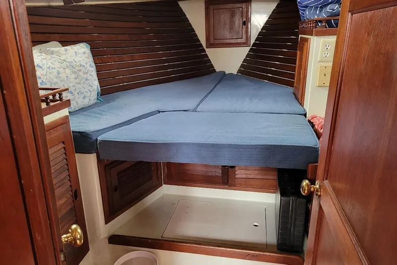 Slide: The Image of 1976 Down East Yachts Cutter cabin interior with blue cushions and wooden cabinetry. - 27