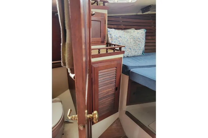 Slide: The Image of 1976 Down East Yachts Cutter interior with wooden cabinetry and blue bedding. - 29