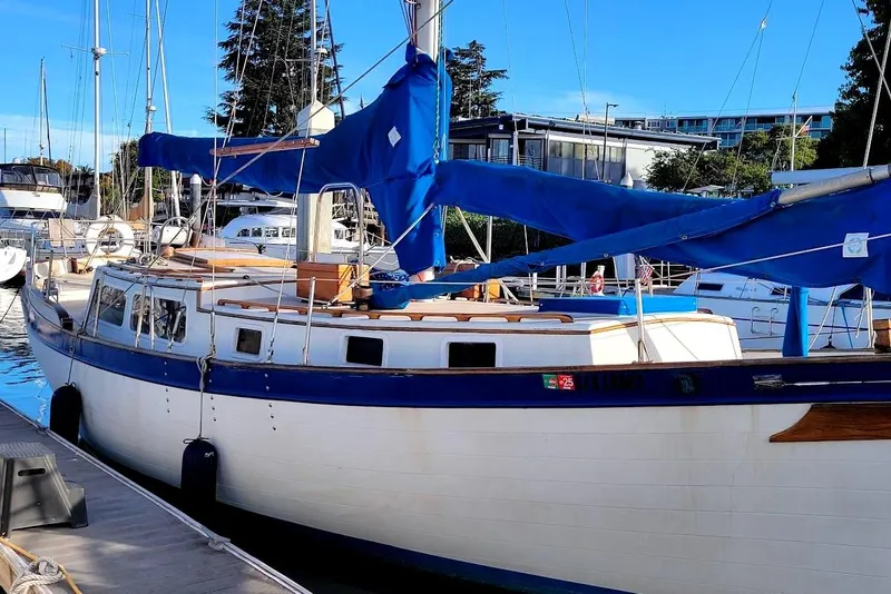 Slide: The Image of 1976 Downeast 38 Cutter sailboat docked, featuring blue sail covers and classic design. - 3