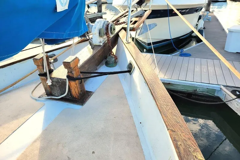 Slide: The Image of 1976 Downeast 38 Cutter sailboat docked, featuring wooden deck details and blue cover. - 5