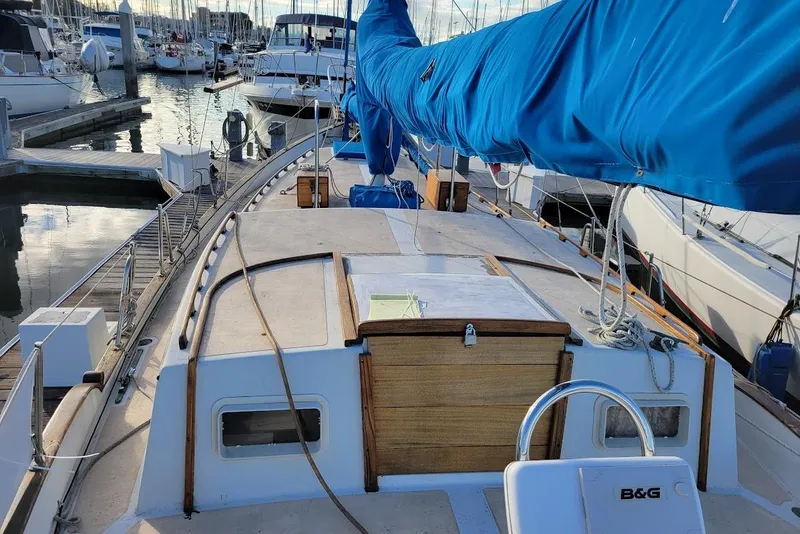 Slide: The Image of 1976 Downeast 38 Cutter sailboat docked in a marina, featuring a blue sail cover. - 6