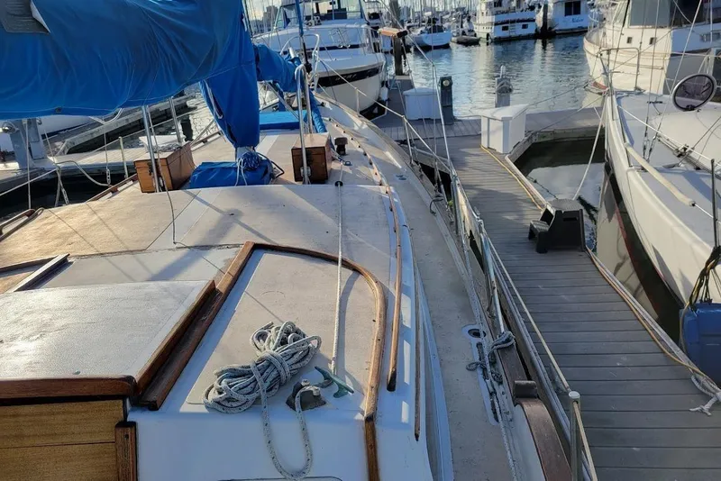 Slide: The Image of 1976 Downeast 38 Cutter sailboat docked at marina, featuring wooden deck and blue sail cover. - 7