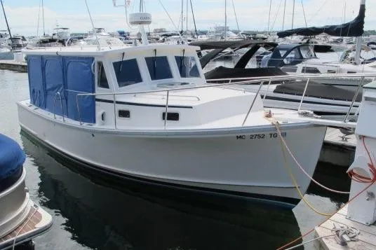 Slide: The Image of 2010 Ellis Downeast Picnic Boat docked at marina, featuring blue canopy and classic design. - 0