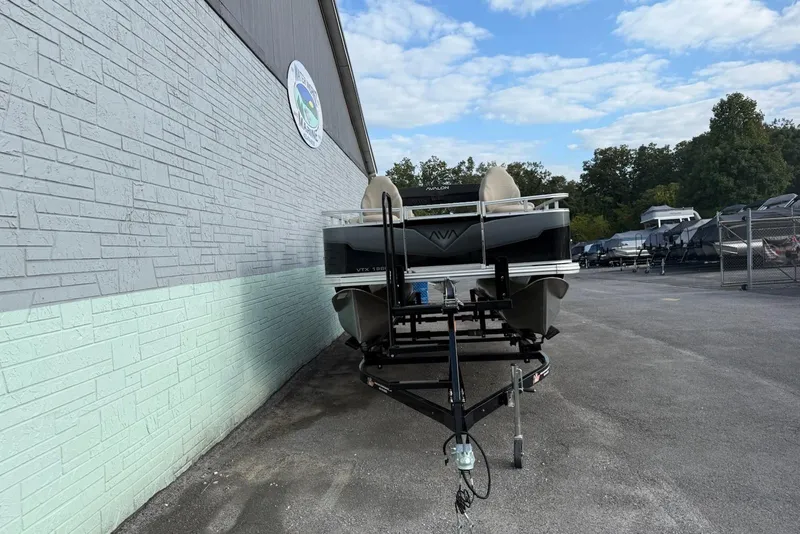 Slide: The Image of 2025 Avalon VTX Quad Fish boat on trailer, parked beside a building under a blue sky. - 2