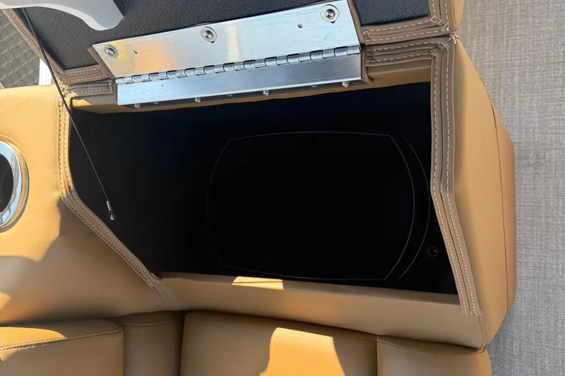 Slide: The Image of Avalon VENTURE QUAD LOUNGER 2026 storage compartment with tan upholstery and metal hinge. - 33