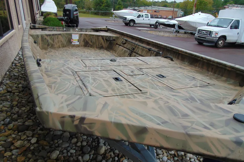 Slide: The Image of 2026 CRESTLINIER 1860 Retriever Deluxe Tiller boat with camouflage design, parked outdoors. - 3