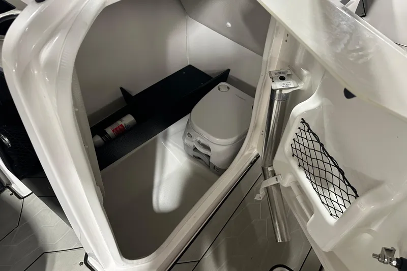 Slide: The Image of 2024 Yamaha Boats 252XE interior storage compartment with portable toilet and accessories. - 16