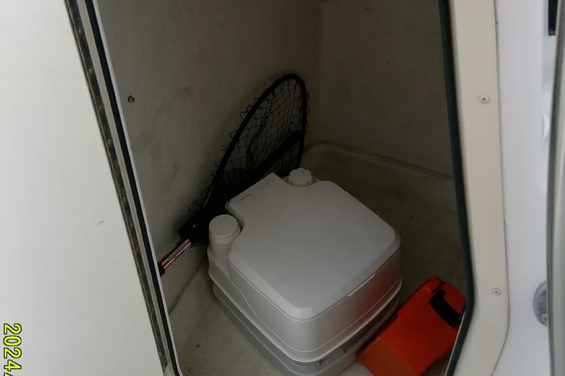 Slide: The Image of Storage compartment in a 2016 Parker 2100 Special Edition boat with portable toilet and fishing net. - 28