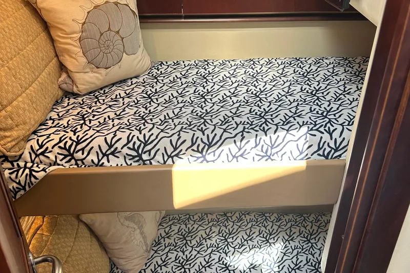 Slide: The Image of 2005 Sea Ray 500 Sedan Bridge cabin with coral-patterned bedding and decorative pillows. - 18