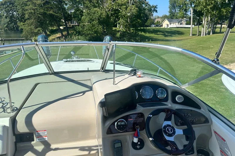 Slide: The Image of 2006 Sea Ray 260 Sundancer boat dashboard with steering wheel and gauges, surrounded by greenery. - 36