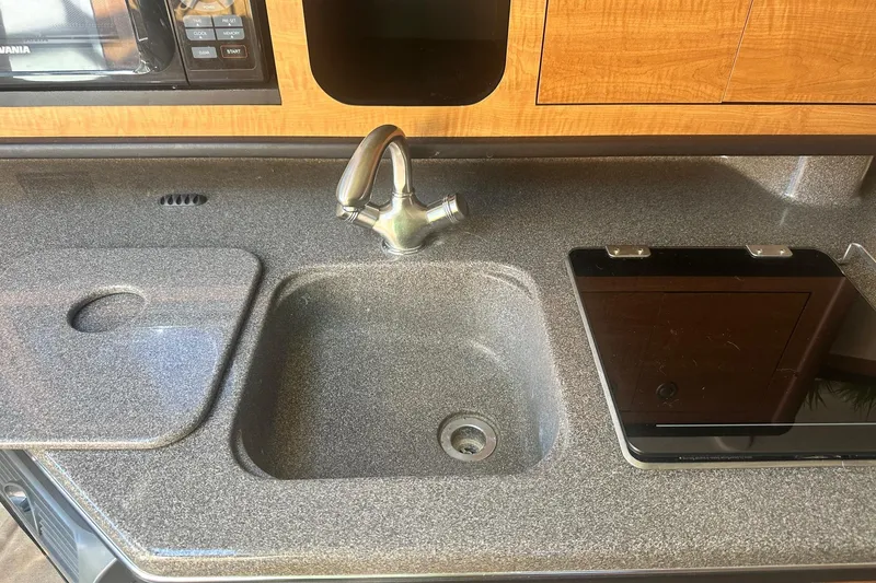 Slide: The Image of Compact kitchen area in a 2006 Sea Ray 260 Sundancer boat, featuring a sink and microwave. - 45