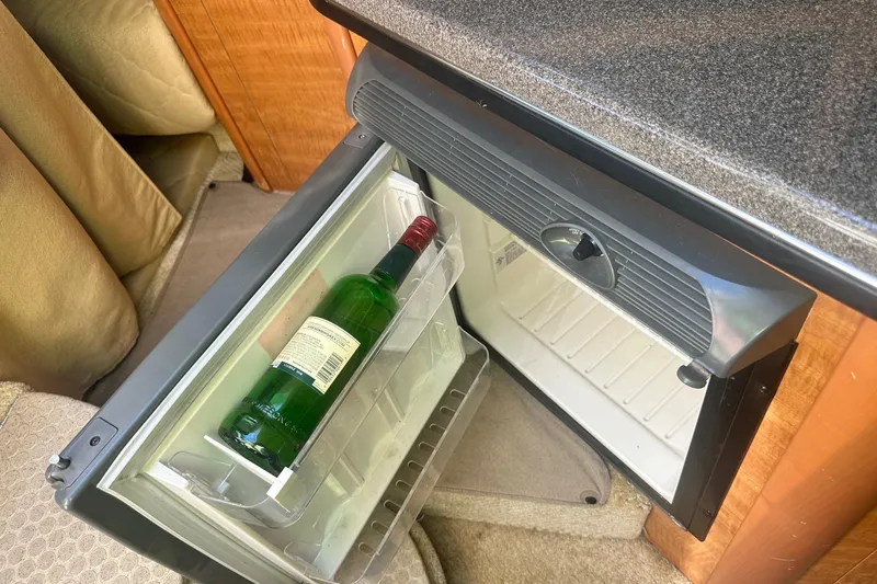 Slide: The Image of Mini fridge with a wine bottle inside a 2006 Sea Ray 260 Sundancer boat cabin. - 46