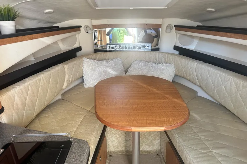 Slide: The Image of Cozy interior of 2006 Sea Ray 260 Sundancer with cushioned seating and wooden table. - 50