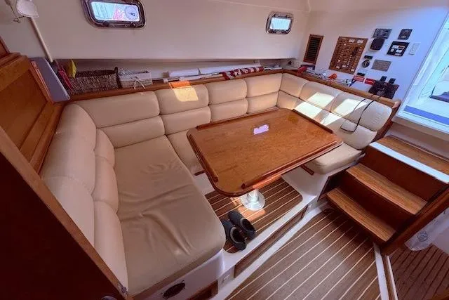 Slide: The Image of 2004 Mainship Pilot 34 interior with beige seating, wooden table, and nautical decor. - 16