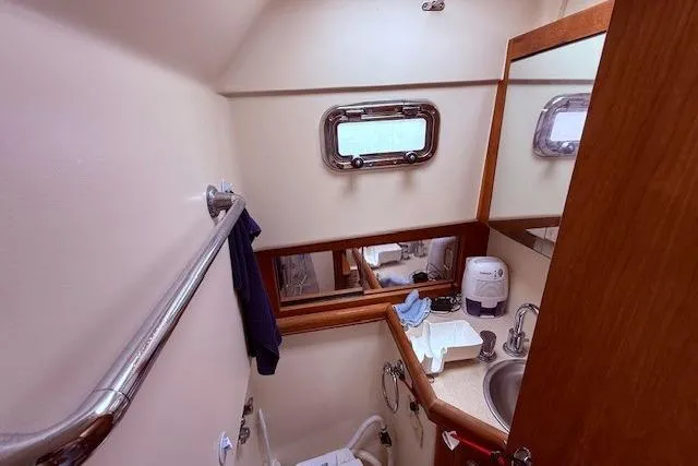 Slide: The Image of 2004 Mainship Pilot 34 boat bathroom with sink, mirror, and porthole window. - 20