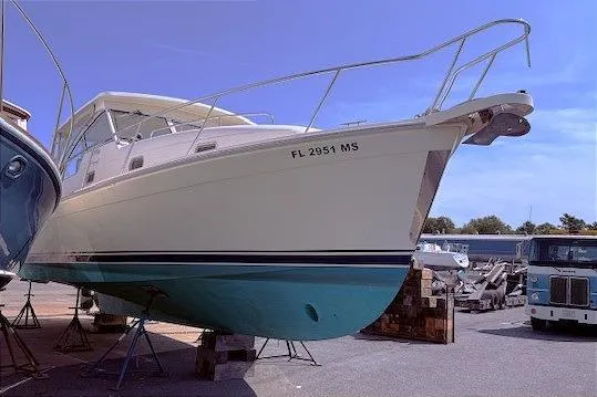 Slide: The Image of 2004 Mainship Pilot 34 boat on stands, white hull with blue bottom, docked outdoors. - 3
