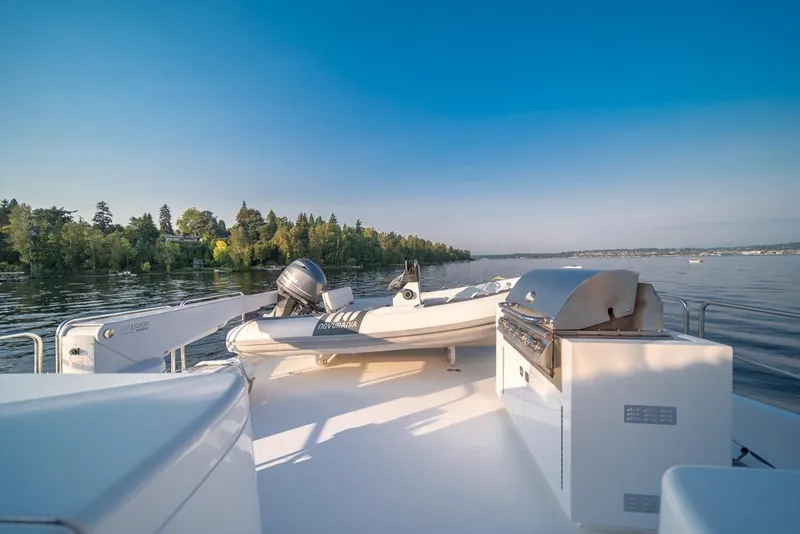 Slide: The Image of 2008 Hatteras 72 Motor Yacht deck with grill and tender on calm water. - 16