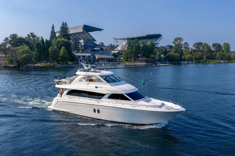 Slide: The Image of 2008 Hatteras 72 Motor Yacht cruising near a stadium and lush greenery. - 7