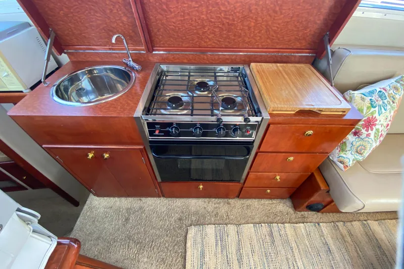 Slide: The Image of Compact kitchen in a 2003 Zeta 36 boat with stove, sink, and wooden cabinetry. - 15