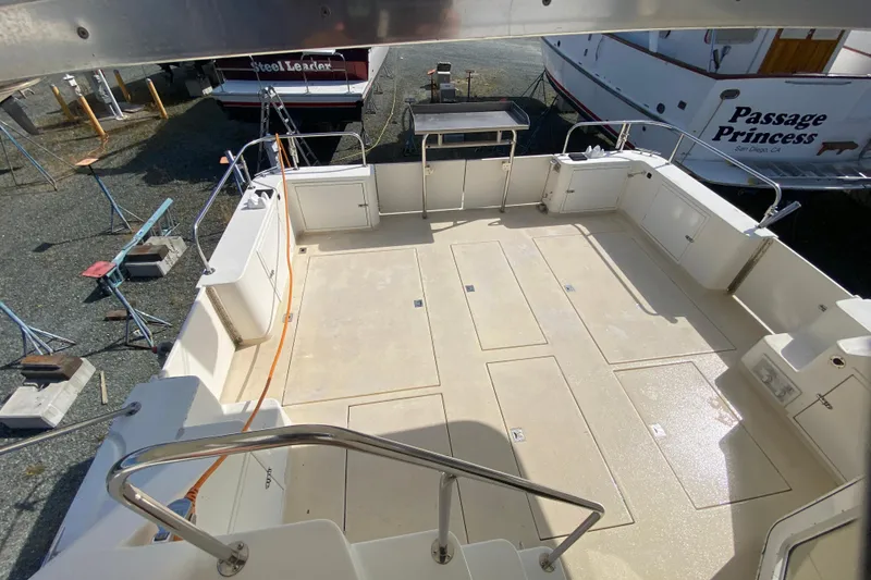 Slide: The Image of 2003 Zeta 36 boat deck with spacious layout and railing, docked near other vessels. - 57