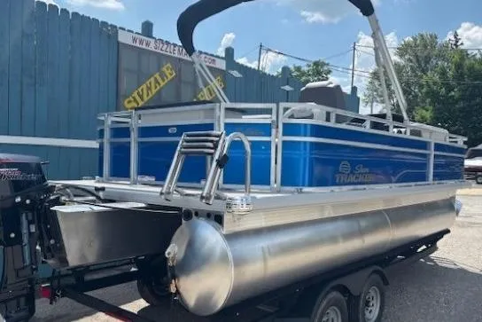 Slide: The Image of 2026 Sun Tracker Fishin' Barge 20 DLX pontoon boat on trailer, blue exterior. - 5