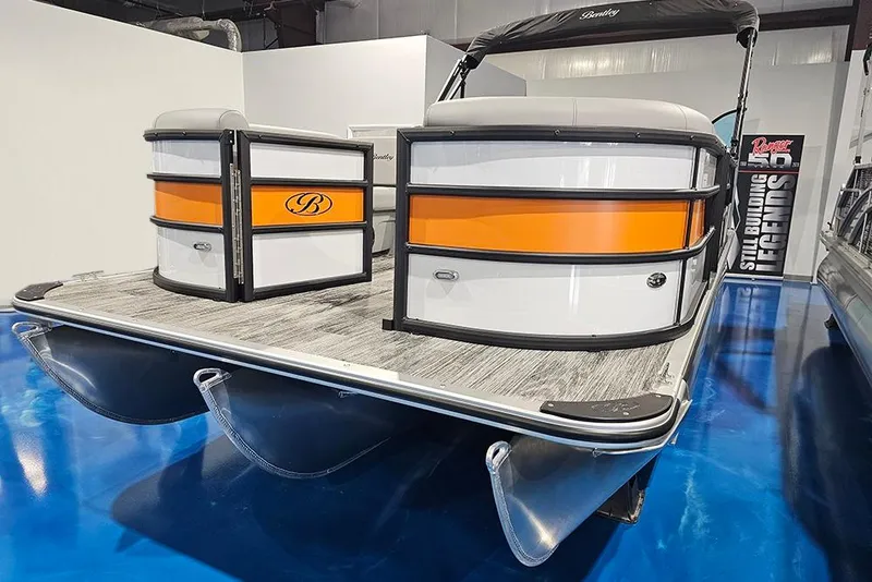 Slide: The Image of 2026 Bentley Pontoons Bolt with orange accents on display indoors. - 2