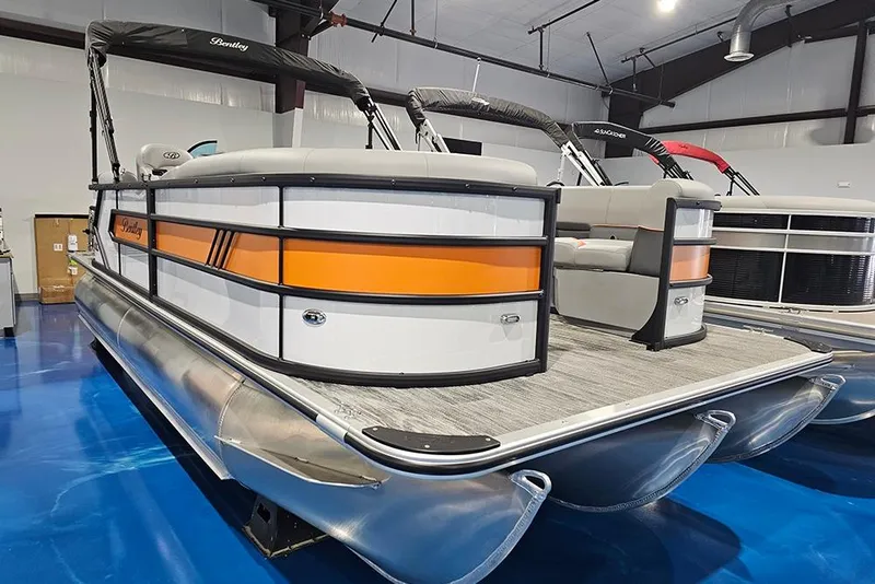 Slide: The Image of 2026 Bentley Pontoons Bolt with orange accents in a showroom. - 3