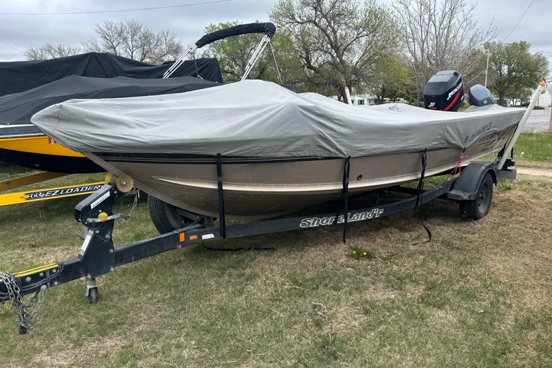 Slide: The Image of 2001 Alumacraft Tournament Pro 185 CS boat covered on trailer, parked on grass. - 2