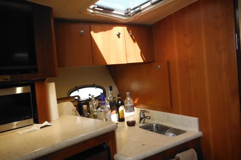 Slide: The Image of 2001 Tiara Yachts 3500 Open interior with kitchenette, sink, and wooden cabinets. - 102