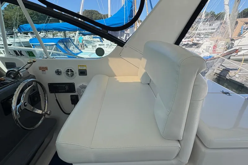 Slide: The Image of 2001 Tiara Yachts 3500 Open cockpit with white seating and steering wheel, docked at marina. - 122