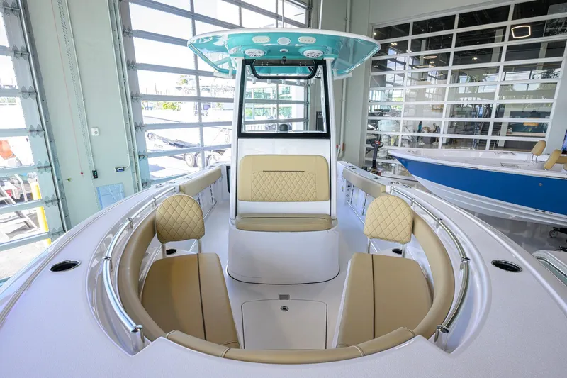 Slide: The Image of 2026 Sportsman Open 212 Center Console boat interior with beige seating in showroom. - 11