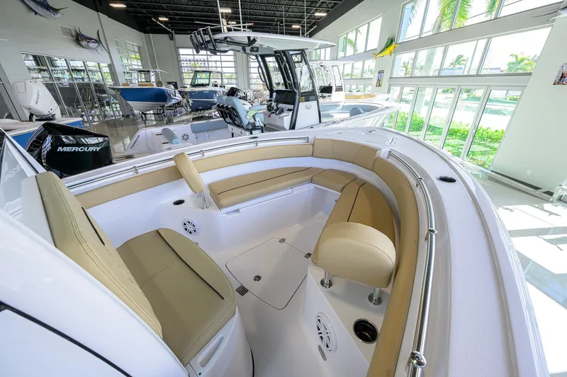 Slide: The Image of 2026 Sportsman Open 212 Center Console boat interior with tan seating in showroom. - 19