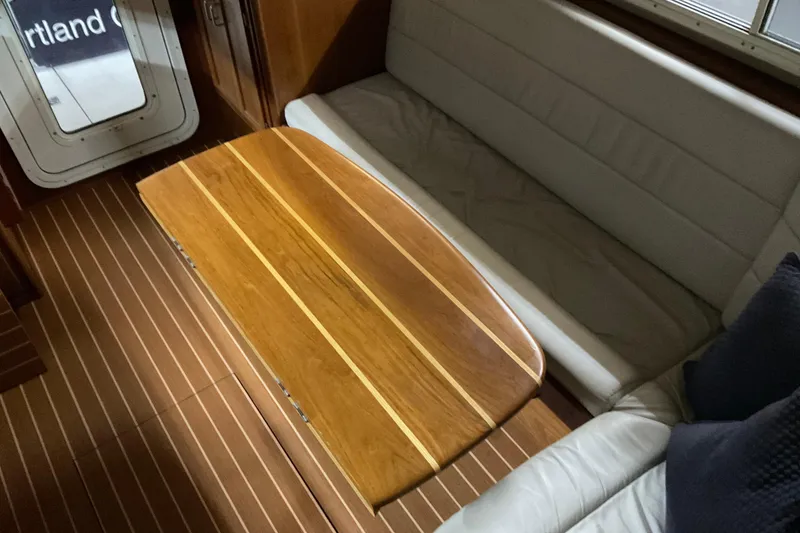 Slide: The Image of Interior of 2002 American Tug Hull #24 with wooden table and cushioned seating. - 10