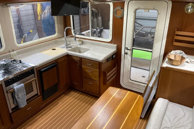 Slide: The Image of Interior of 2002 American Tug Hull #24, featuring a cozy kitchen and dining area. - 11