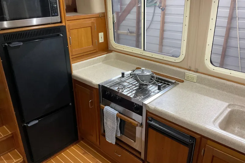 Slide: The Image of Cozy 2002 American Tug kitchen with stove, fridge, and wooden cabinetry. - 12