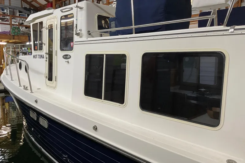 Slide: The Image of 2002 American Tug Hull #24 docked indoors, showcasing sleek design and large windows. - 4