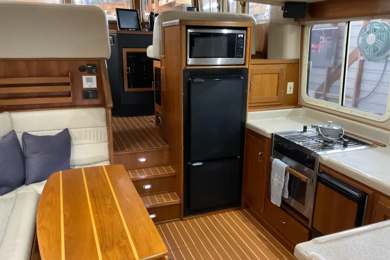 Slide: The Image of Interior of 2002 American Tug Hull #24, featuring kitchen and seating area with wood accents. - 5