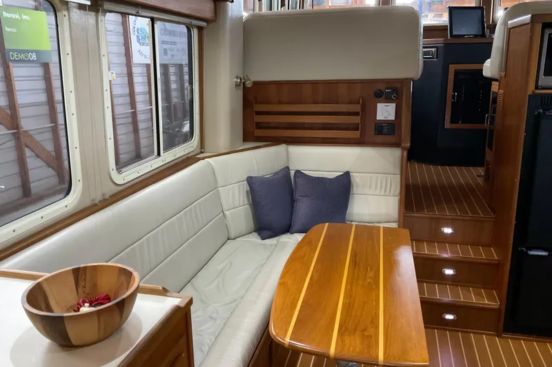 Slide: The Image of Interior of 2002 American Tug Hull #24 with wooden table and cushioned seating. - 7