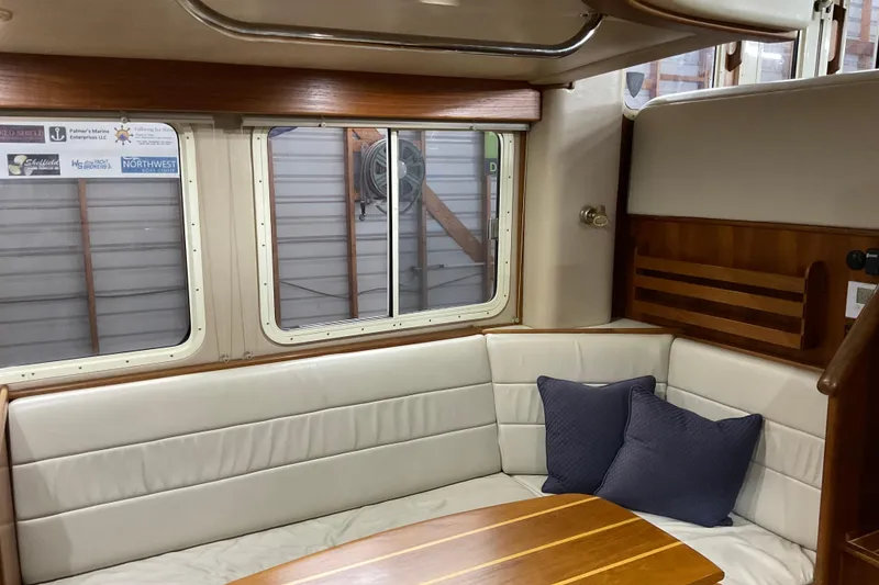 Slide: The Image of Cozy interior of 2002 American Tug Hull #24 with cushioned seating and wooden table. - 8