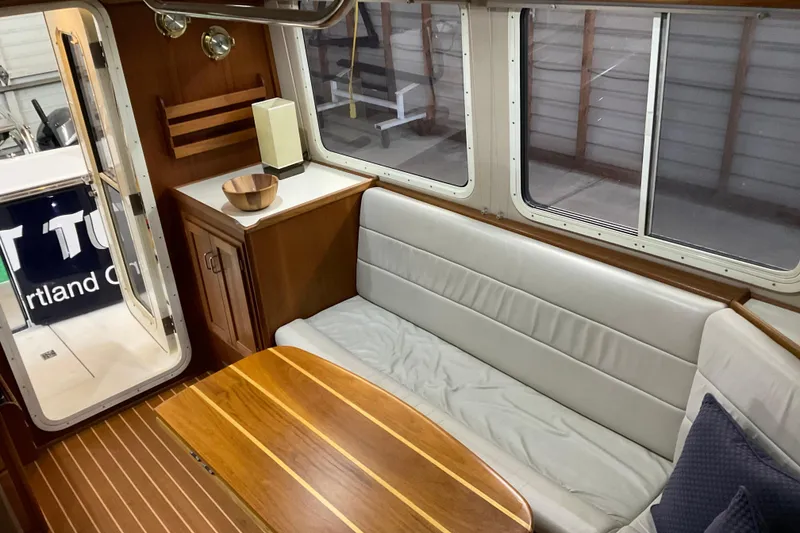 Slide: The Image of Interior of 2002 American Tug Hull #24 with wooden table and cushioned seating. - 9