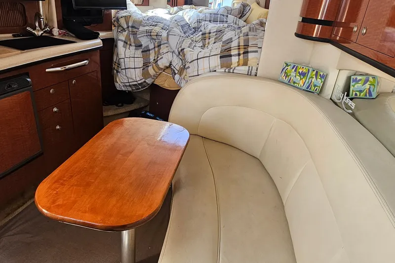 Slide: The Image of Interior of 2005 Sea Ray 300 Sundancer with cozy seating and wooden table. - 11