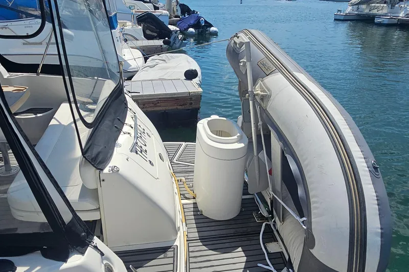 Slide: The Image of 2005 Sea Ray 300 Sundancer docked with inflatable boat and marina view. - 13