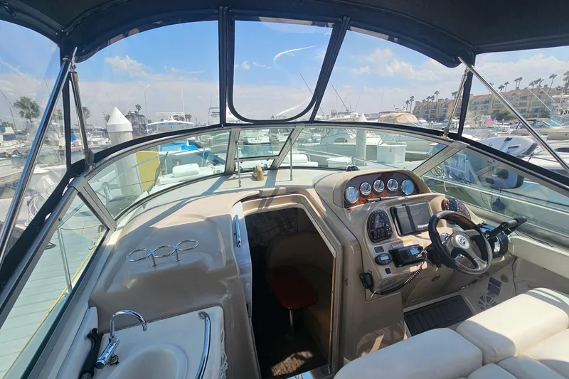 Slide: The Image of 2005 Sea Ray 300 Sundancer cockpit with steering wheel, gauges, and marina view. - 3