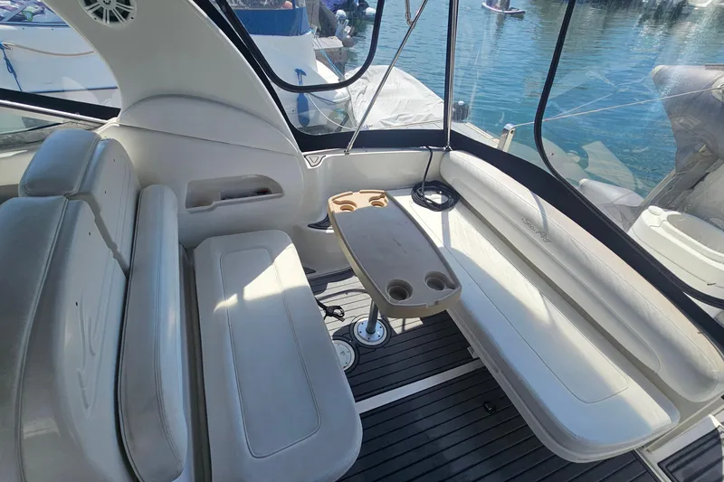 Slide: The Image of 2005 Sea Ray 300 Sundancer interior with seating and table, docked by the water. - 5