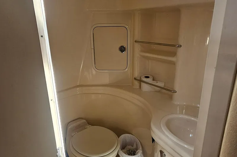Slide: The Image of 2005 Sea Ray 300 Sundancer bathroom with toilet, sink, and storage shelves. - 7