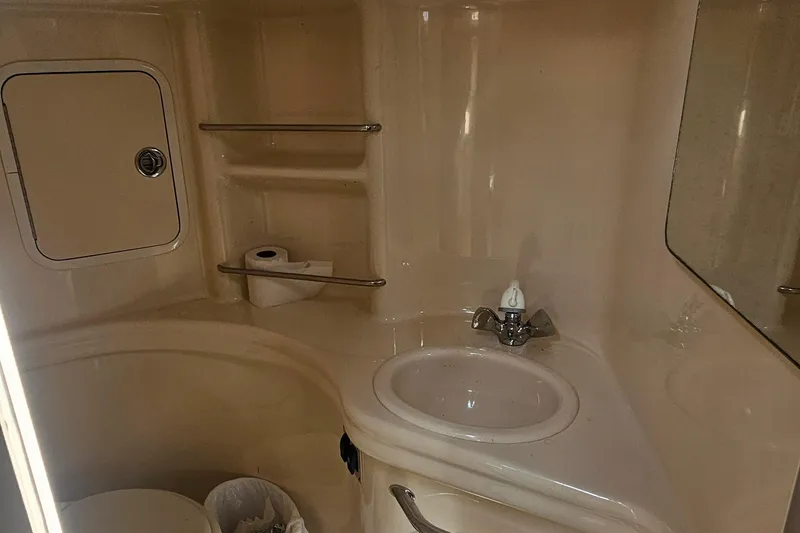 Slide: The Image of 2005 Sea Ray 300 Sundancer bathroom with sink, mirror, and storage shelves. - 8