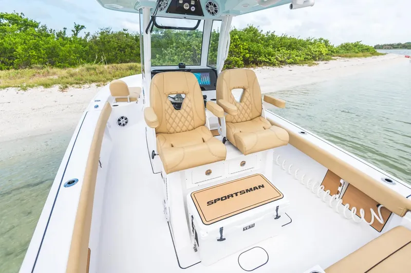 Slide: The Image of 2026 Sportsman Masters 267 Bay Boat interior with tan seating, near sandy shore. - 16